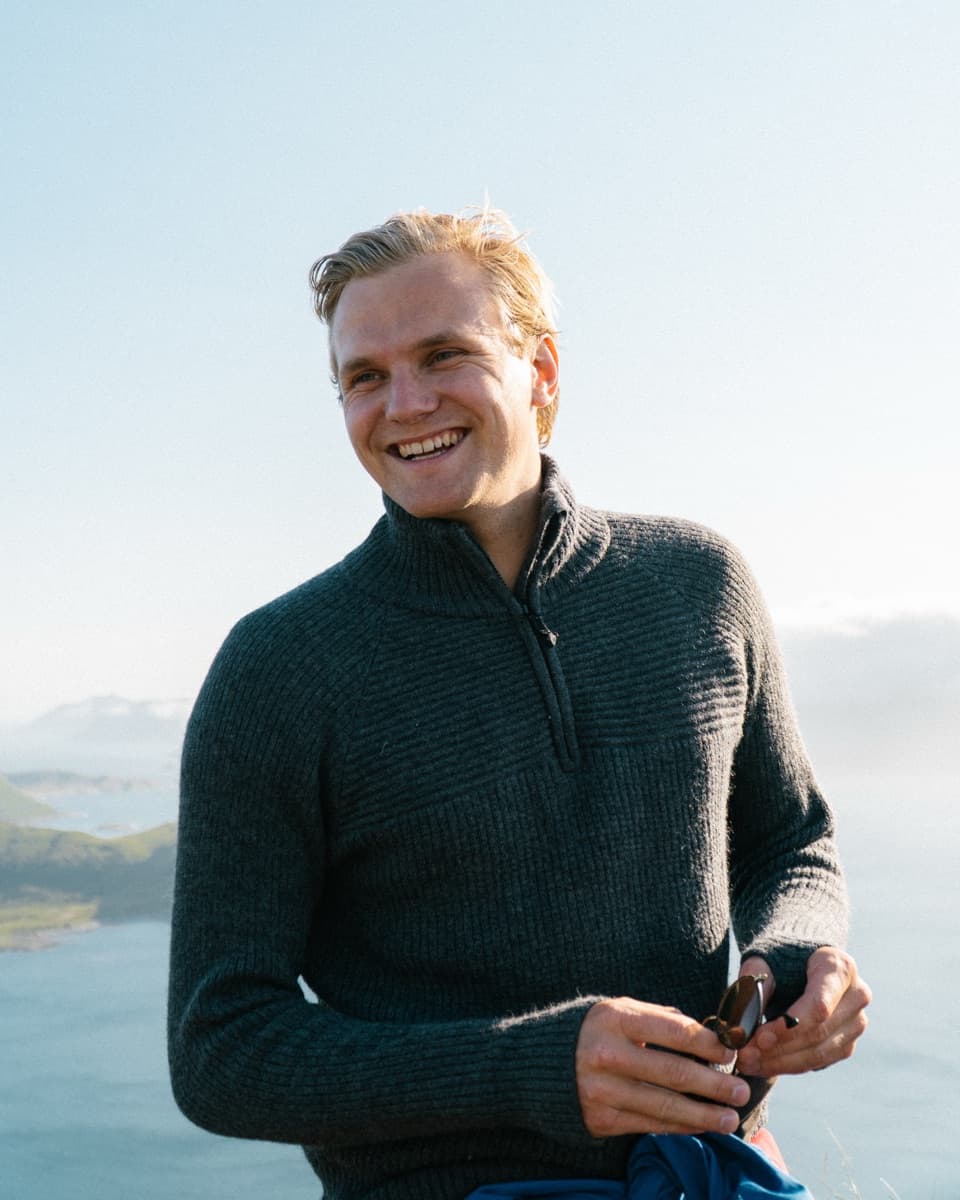 Petter Haga smiling on a mountain top above the sea in Norway